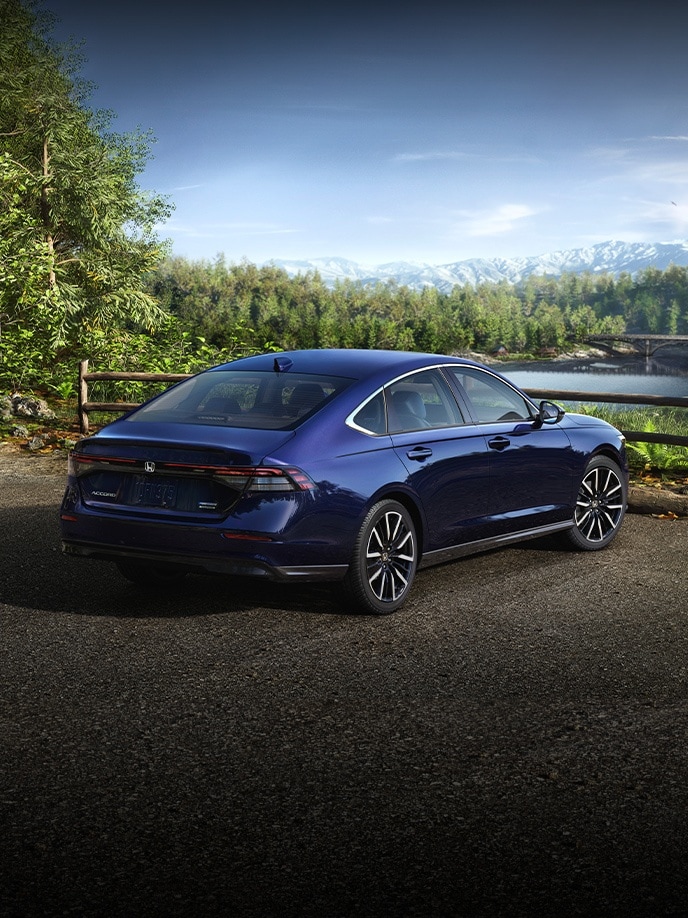 2025 Honda Accord Hybrid parked near a lake in Canyon River Blue Metallic
