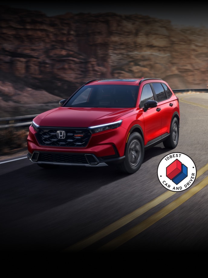 2026 Honda CR-V TrailSport Hybrid in Radiant Red Metallic front view with overlapping Car and Driver 10Best logo (Compact Crossover SUV).