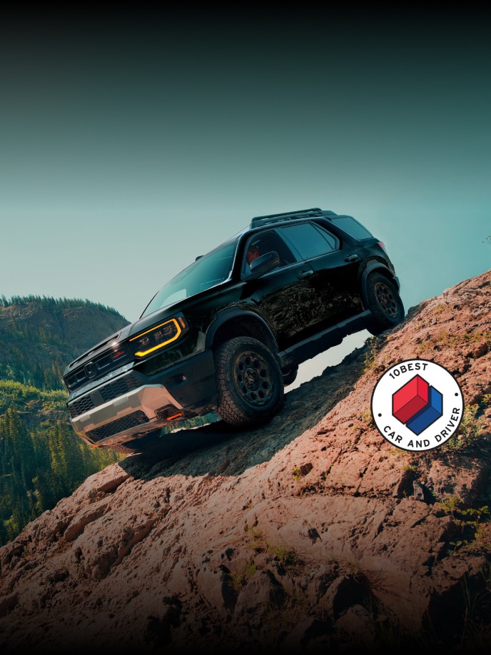 2026 Honda Passport TrailSport Elite in Crystal Black Pearl front 3/4 angle with overlapping Car and Driver 10Best logo (Mid-Size SUV).