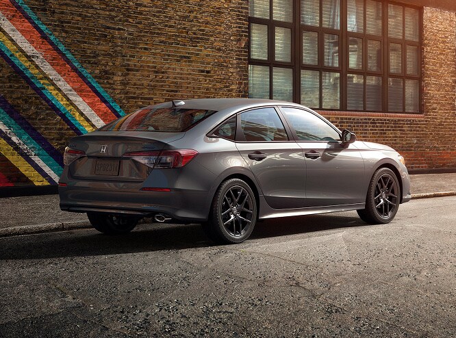 2026 Honda Civic Sedan Sport in Meteorite Gray Metallic rear three-quarter view parked on a city street (Compact Sedan)